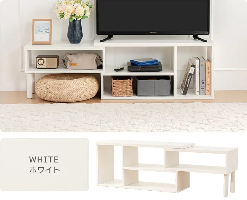 白いテレビ台の写真です。テレビ台の上にはテレビ、花瓶、写真立てなどが置かれています。テレビ台の下には、ラジオ、かばん、クッション、収納ボックス、本などが置かれています。