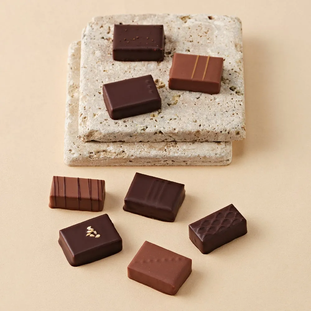 チョコレートがいくつか並べられた写真。チョコレートは様々な形状とデザインで、石のような台の上に置かれている。