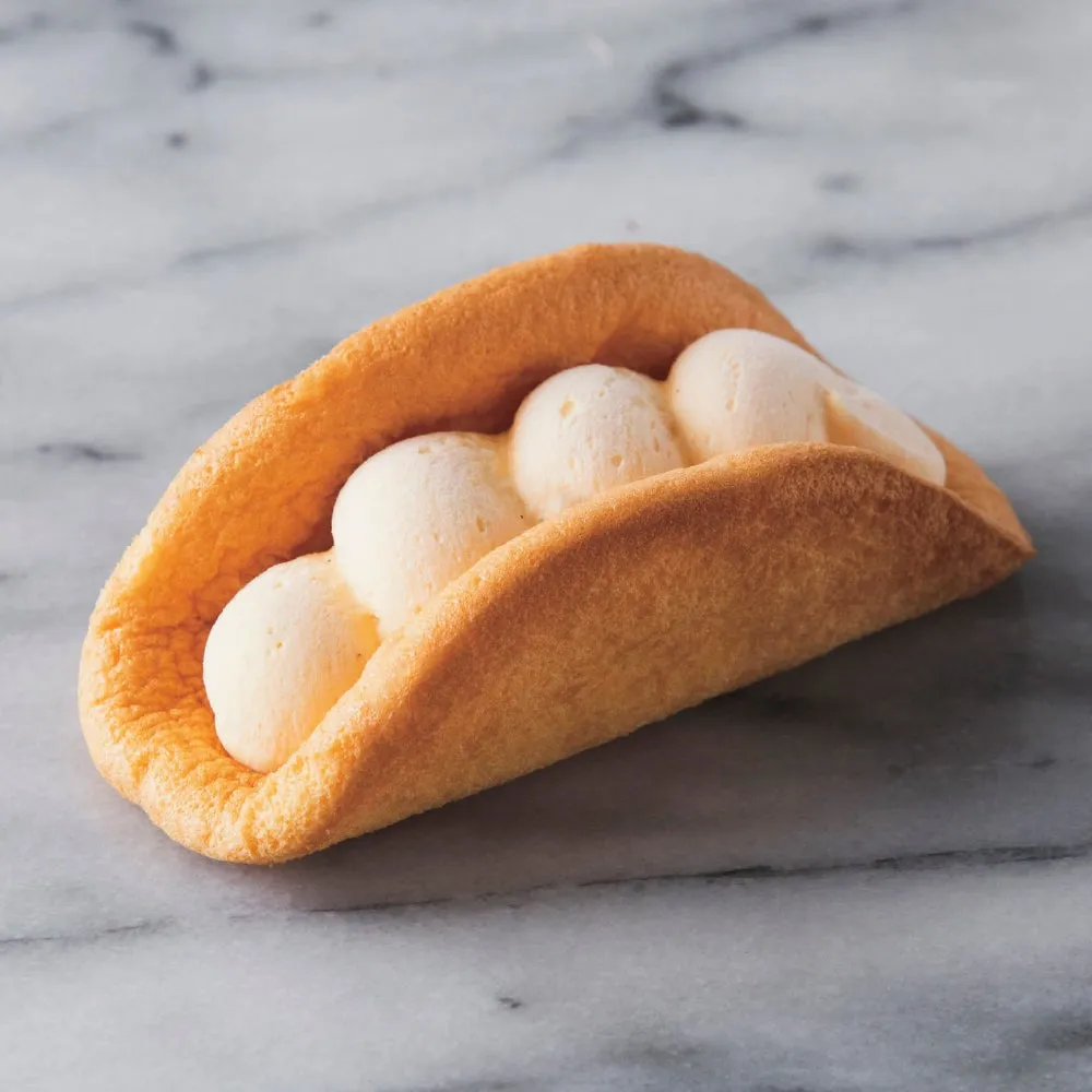 デザートのクローズアップ写真。クリームが詰まった焼き菓子が、大理石のテーブルの上に置かれている。