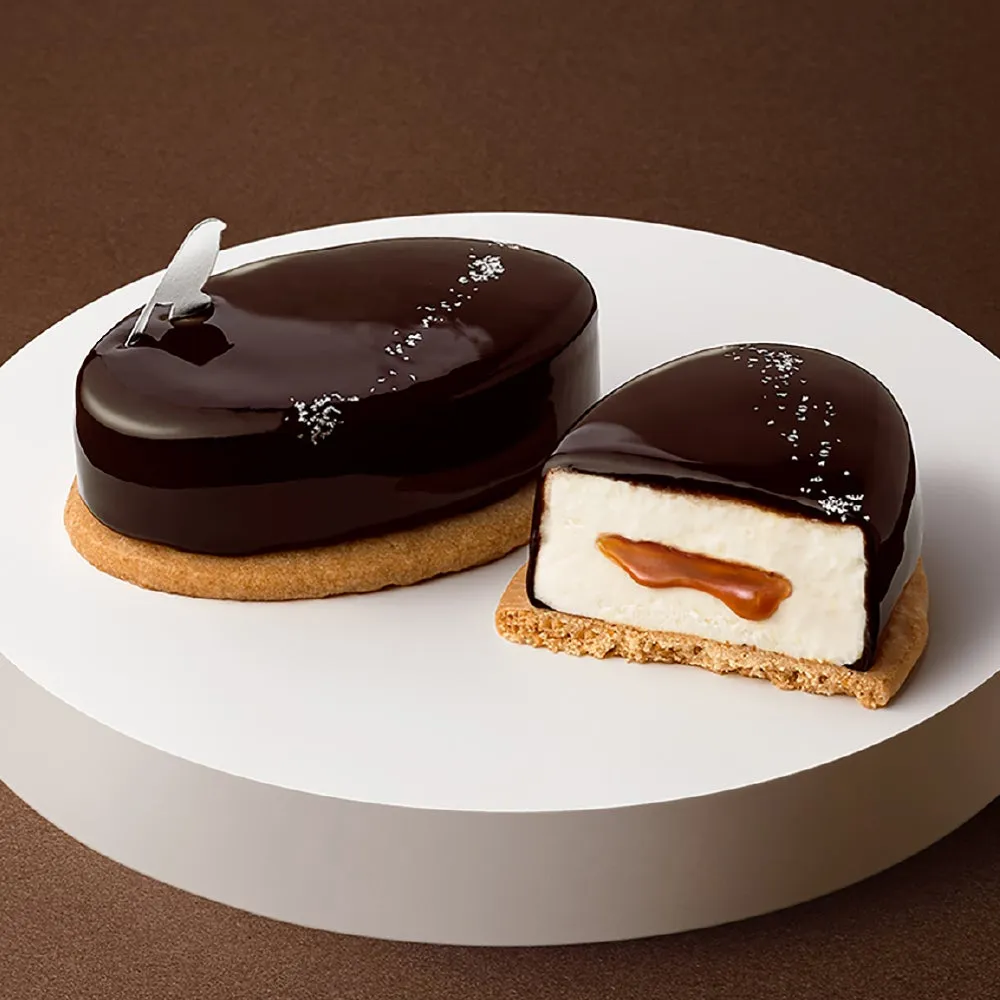 チョコレートケーキが2つ。一つは丸ごと、もう一つは半分に切られており、中身が見える。白いクリームとキャラメルソースが入っている。