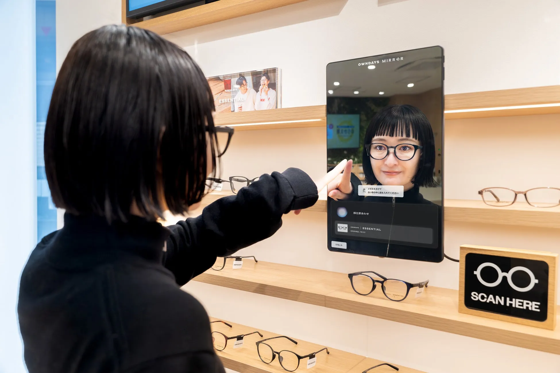 女性が鏡に映る自分の顔を見ながら眼鏡を試着している様子