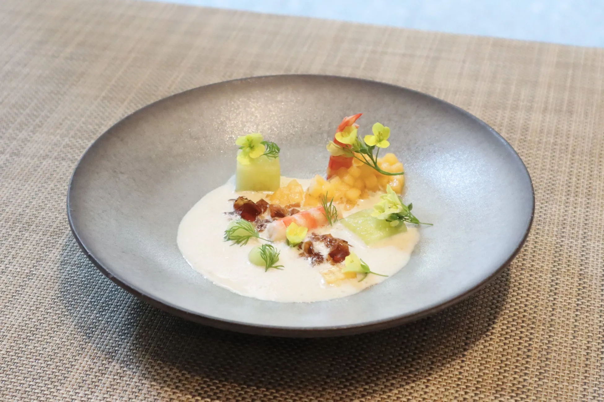 エビと果物、緑色の野菜と花が添えられた料理