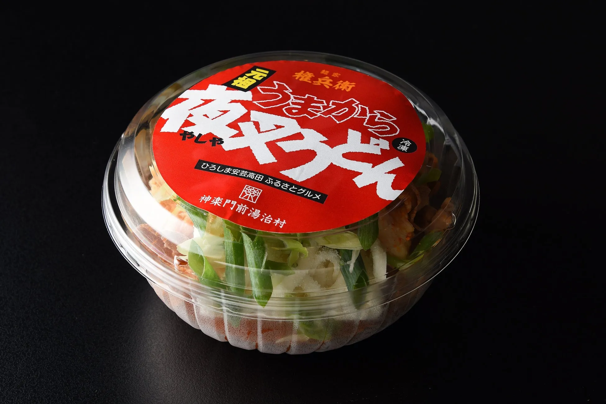 透明な容器に入った夜叉うどん。赤いラベルには「うまから夜叉うどん」と書かれており、麺や具材が見える。