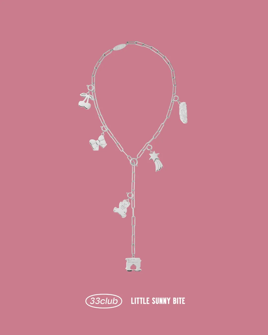 ピンクの背景に、様々なチャームが付いた銀色のネックレスが複数。