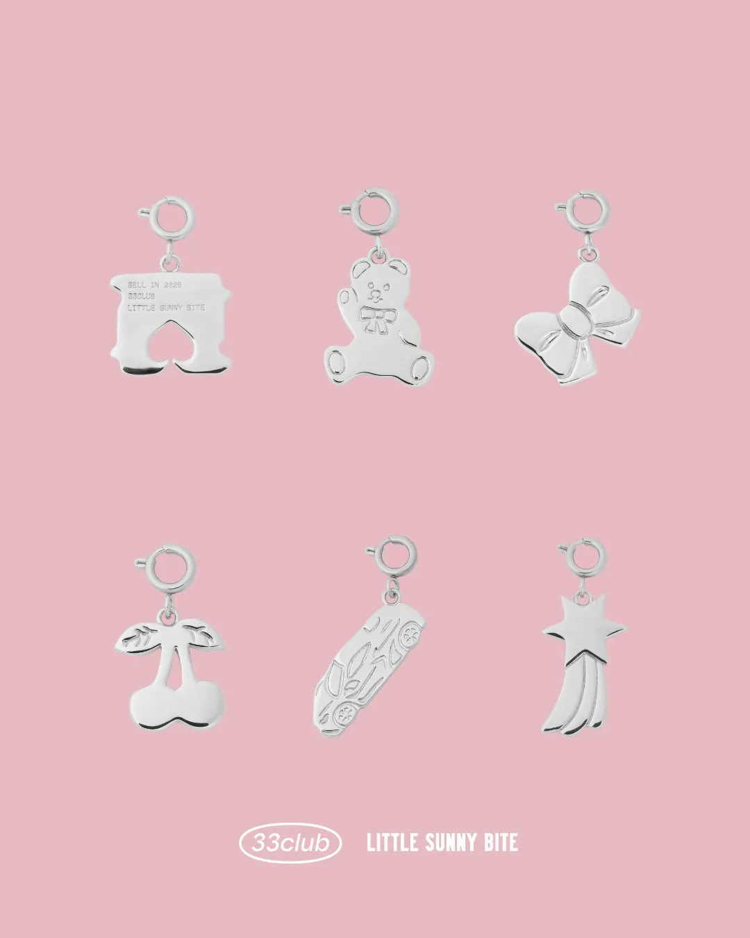 ピンクの背景に、クマ、リボン、さくらんぼ、車、流れ星、ロゴなど可愛らしいモチーフのシルバーチャームがずらりと並んでいます。