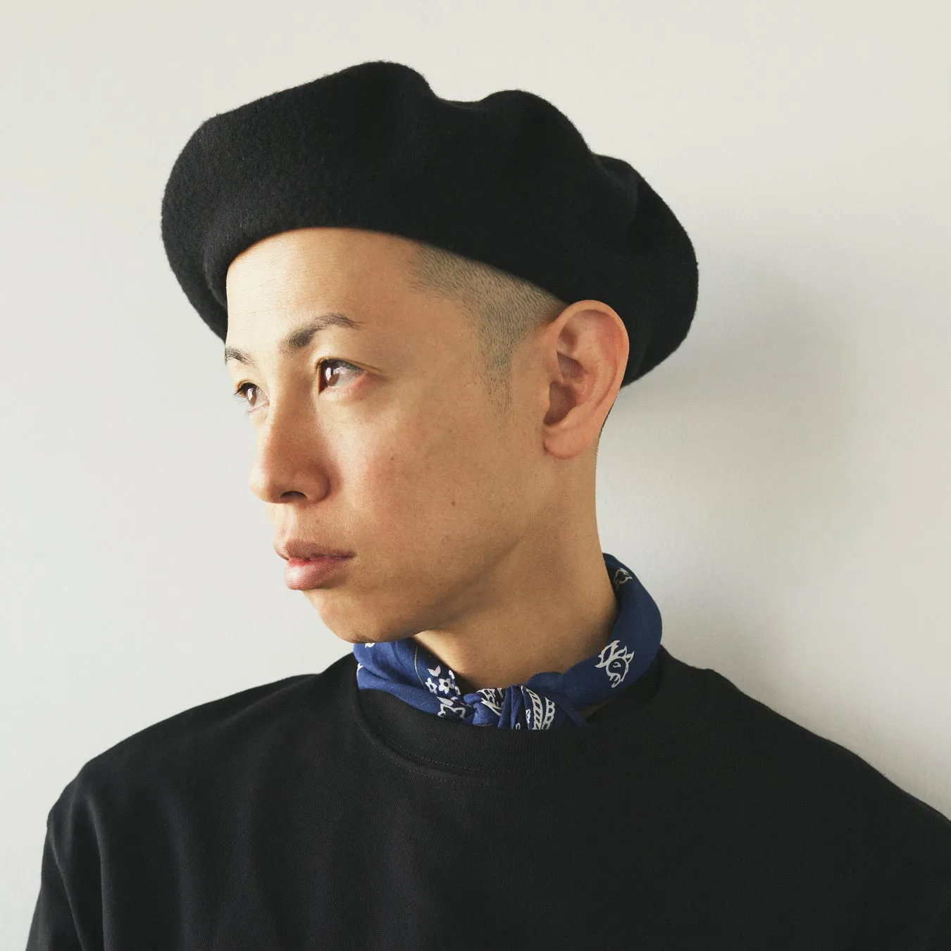 黒いベレー帽をかぶり、青いバンダナを首に巻いた男性のポートレート
