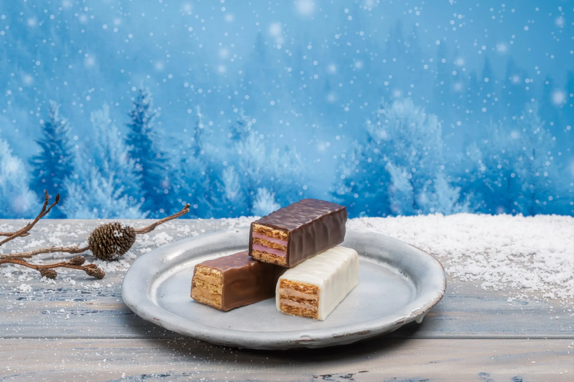 雪景色の中に、チョコレートでコーティングされたお菓子が3つ、お皿に載せられています。