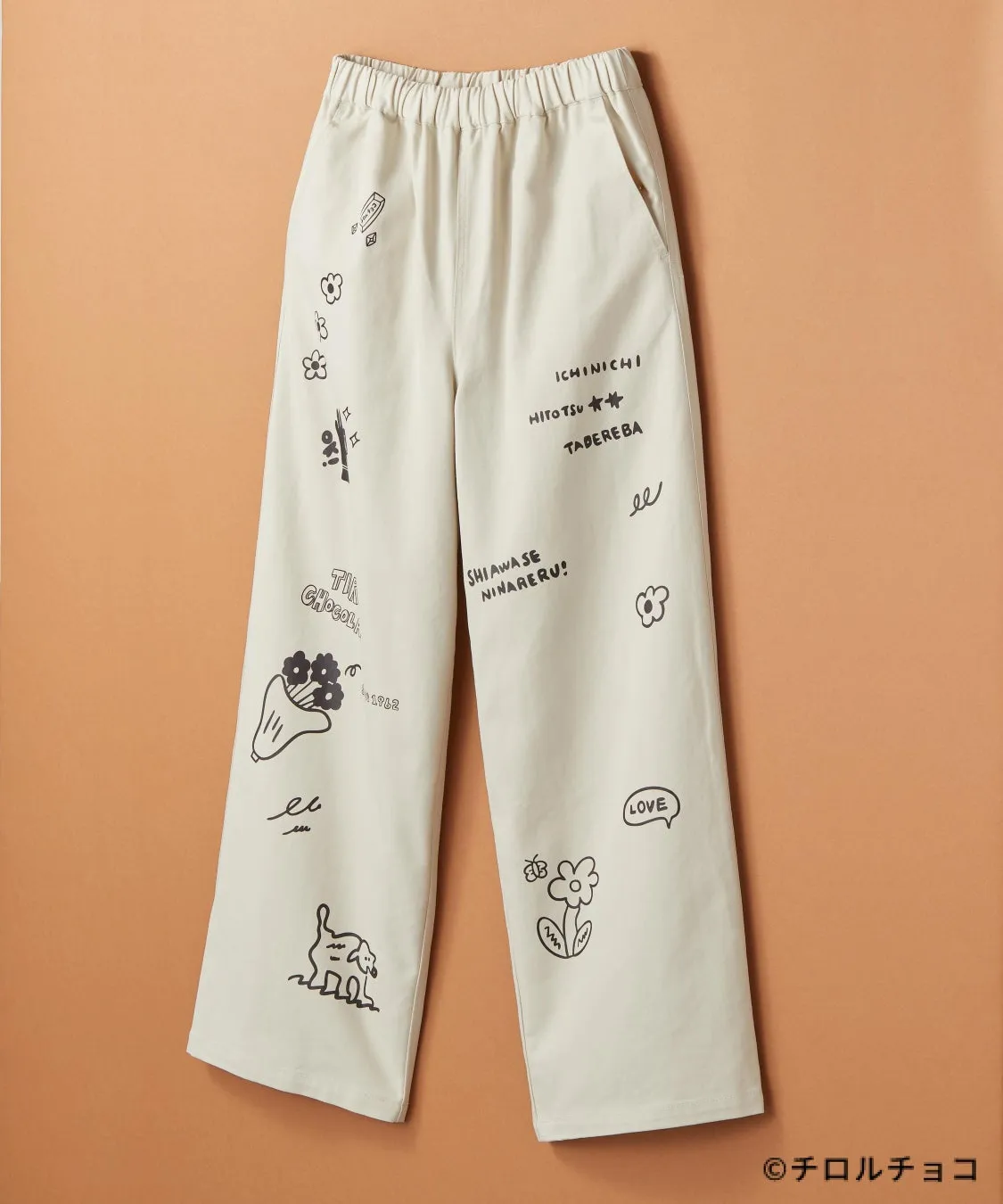 ベージュ色のパンツに手書き風のイラストと文字が描かれた写真。イラストは花、動物、吹き出しなど。文字は日本語と英語が混ざっている。