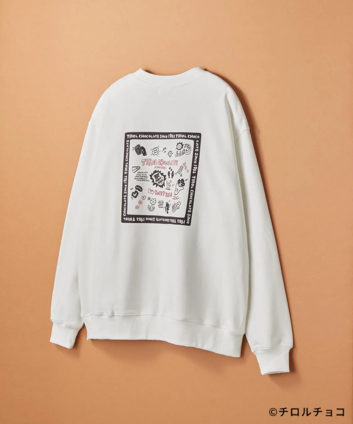 白いトレーナーの背面に、チロルチョコのイラストと文字がプリントされている。周りにはチロルチョコのロゴや関連する言葉が配置されている。