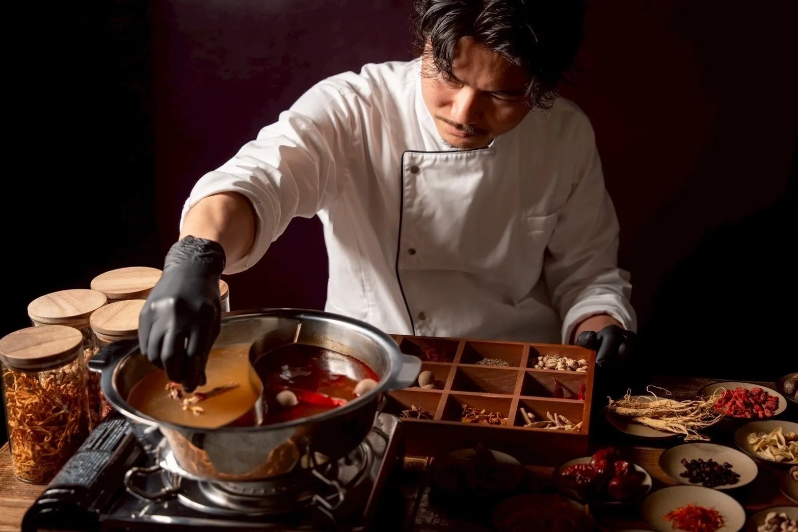 料理人が鍋に食材を加えている様子