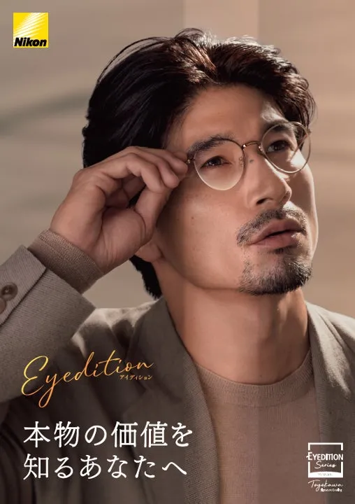 男性が眼鏡をかけ、眼鏡を調整している様子を捉えた広告画像です。背景は暖色系のグラデーションで、全体的に落ち着いた印象を与えます。