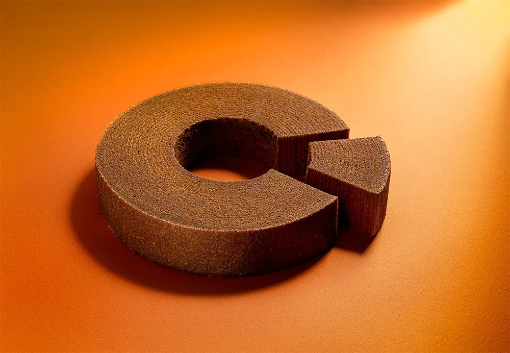 バウムクーヘンが置かれた写真。バウムクーヘンの一部が切り取られており、オレンジ色の背景に配置されています。