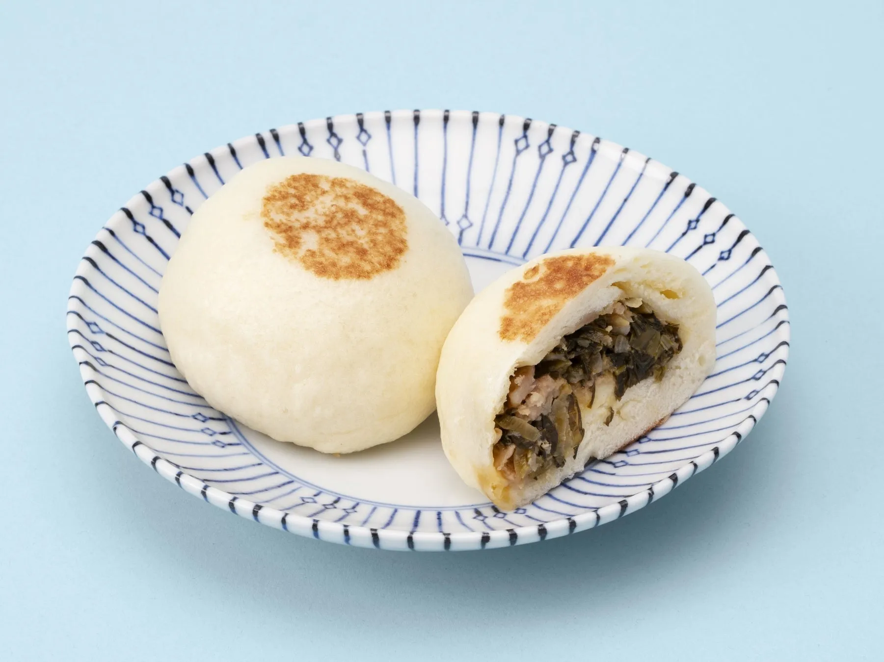 お皿に乗った、焼き目がついた中華まんの画像。半分に切られた中華まんからは具材が見える。