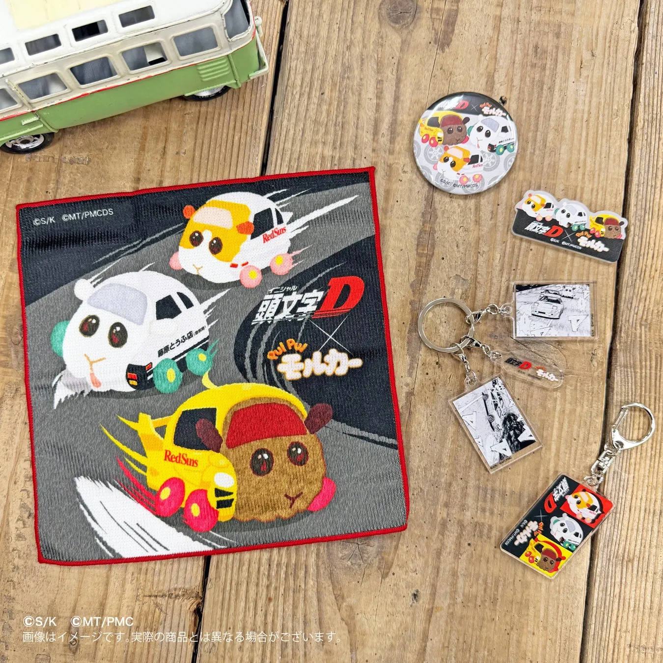 木製のテーブルの上に、アニメ「頭文字D」と「モルカー」のコラボグッズが並べられた写真。