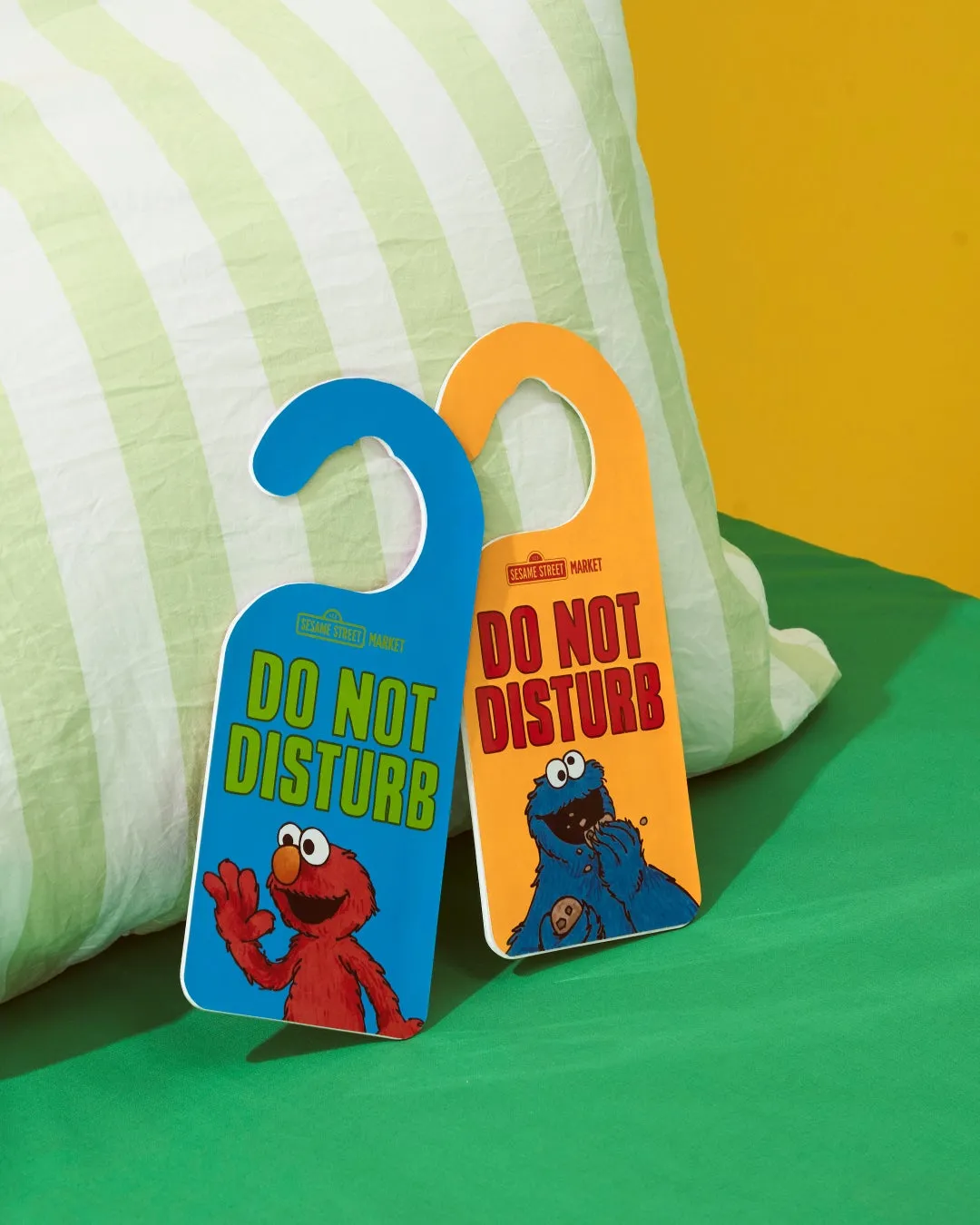セサミストリートのキャラクターであるエルモとクッキーモンスターが描かれた、青とオレンジ色の「DO NOT DISTURB」のドアノブプレートが写っている写真。