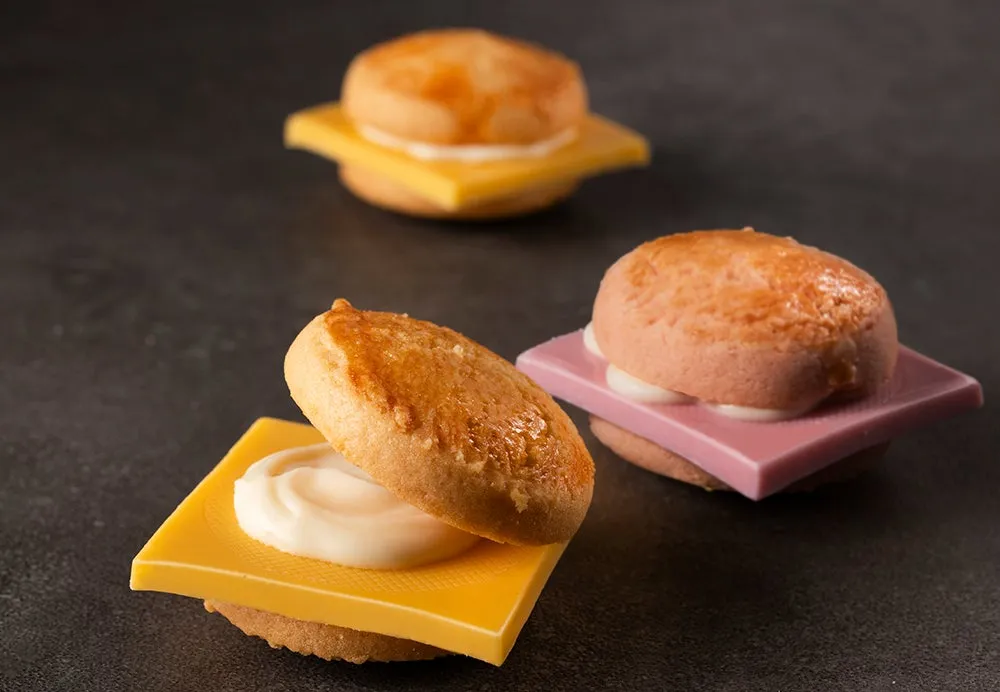 3つのミニサンドイッチが並んだ写真。サンドイッチは、パン、チーズ、クリームで構成されている。