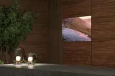 木目調の壁に囲まれた空間に、緑の植物とキャンドルが置かれ、壁には風景画が飾られています。