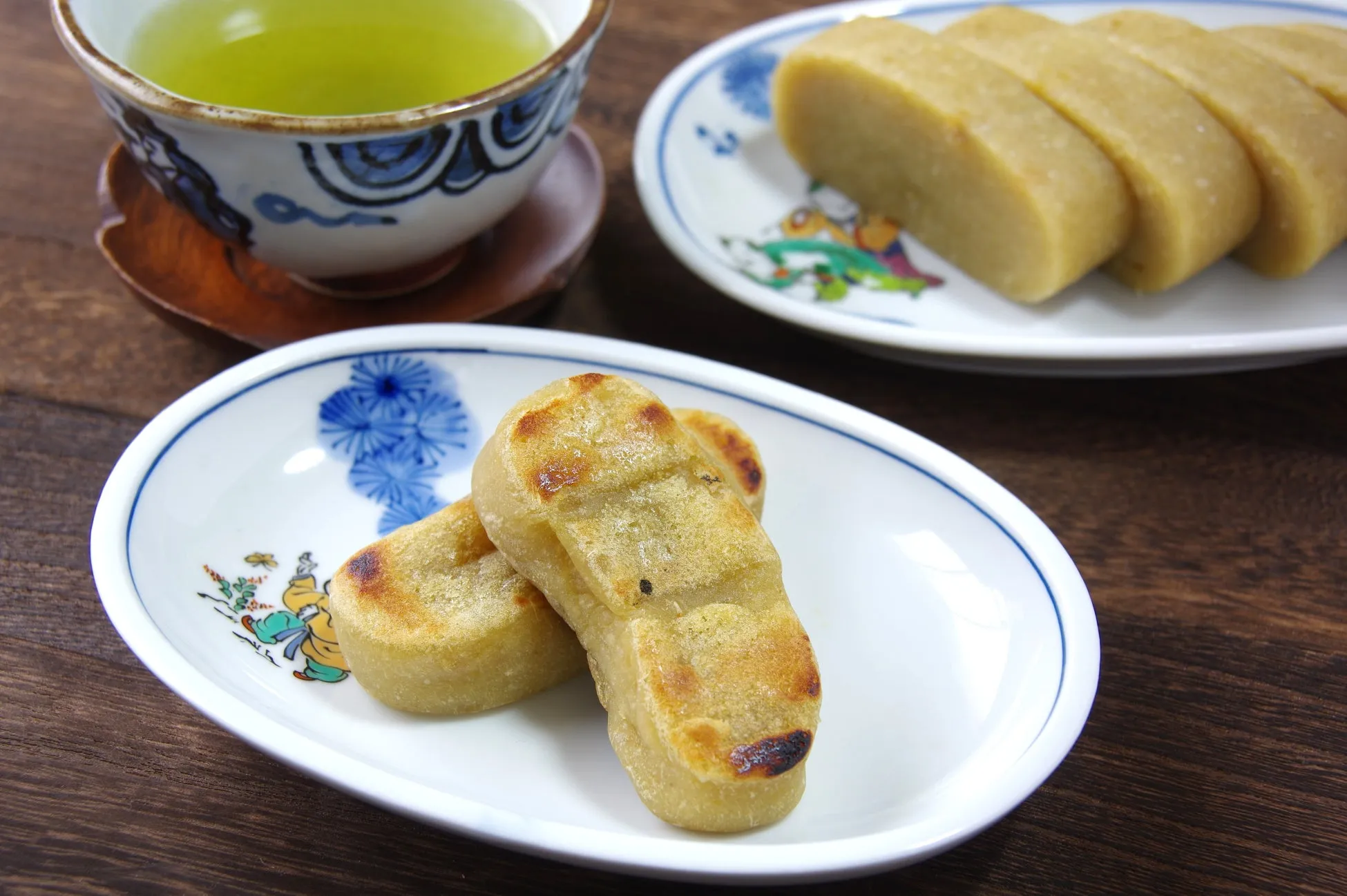 お茶と和菓子が写った写真。白いお皿に和菓子が2つ、別の皿には細長い和菓子がいくつか並んでいる。奥にはお茶が入った湯呑みが見える。