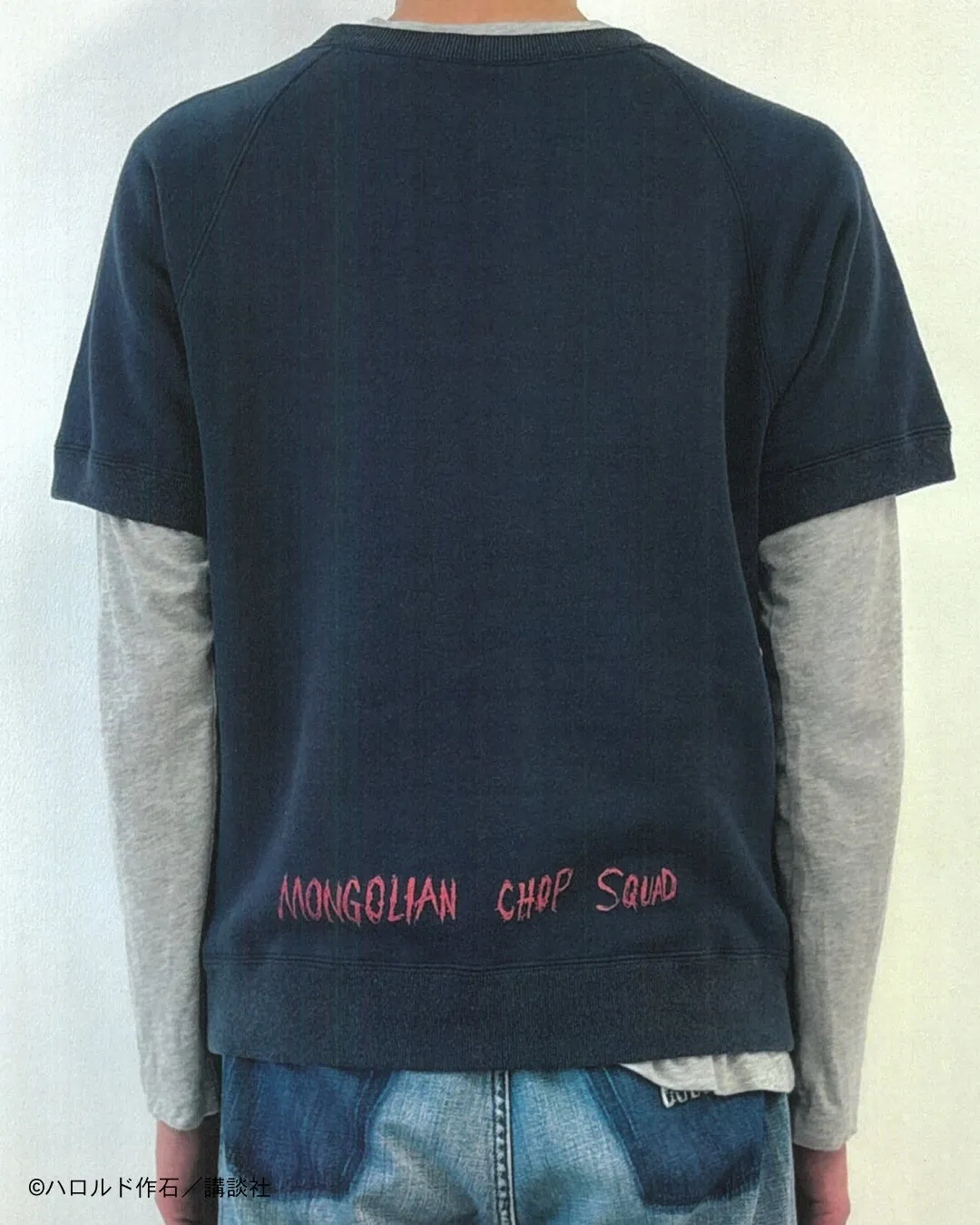 男性が着ているTシャツの背面の写真。Tシャツには「MONGOLIAN CHOP SQUAD」の文字がプリントされており、著作権表示も含まれています。