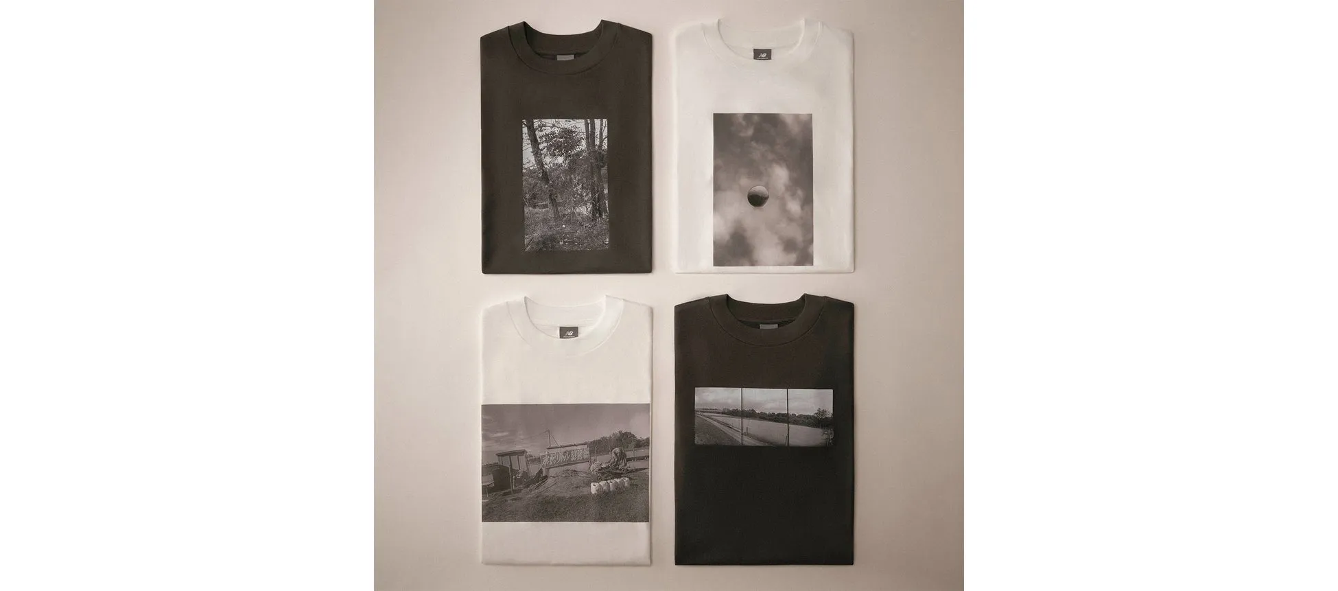 4枚のTシャツが並べられた写真です。それぞれのTシャツには、白黒の写真がプリントされています。上段左は森の写真、上段右は雲と球体の写真、下段左は建物と人の写真、下段右は川沿いの道の写真です。