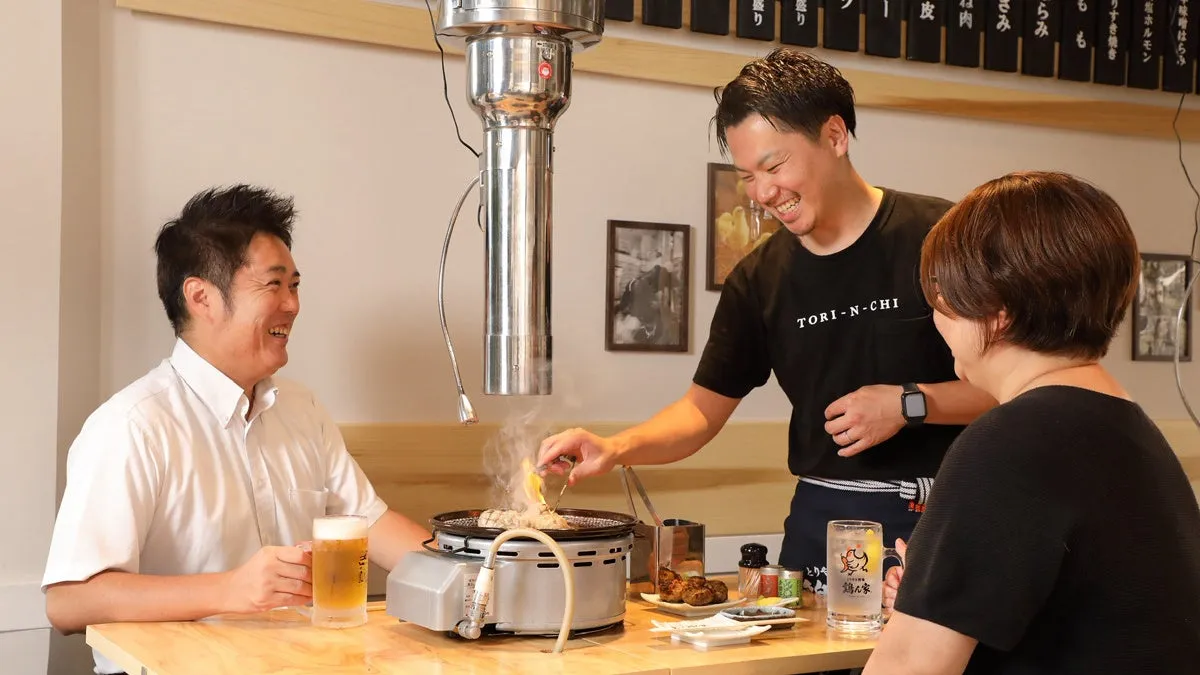 焼肉屋で、店員が客に肉を焼いている様子