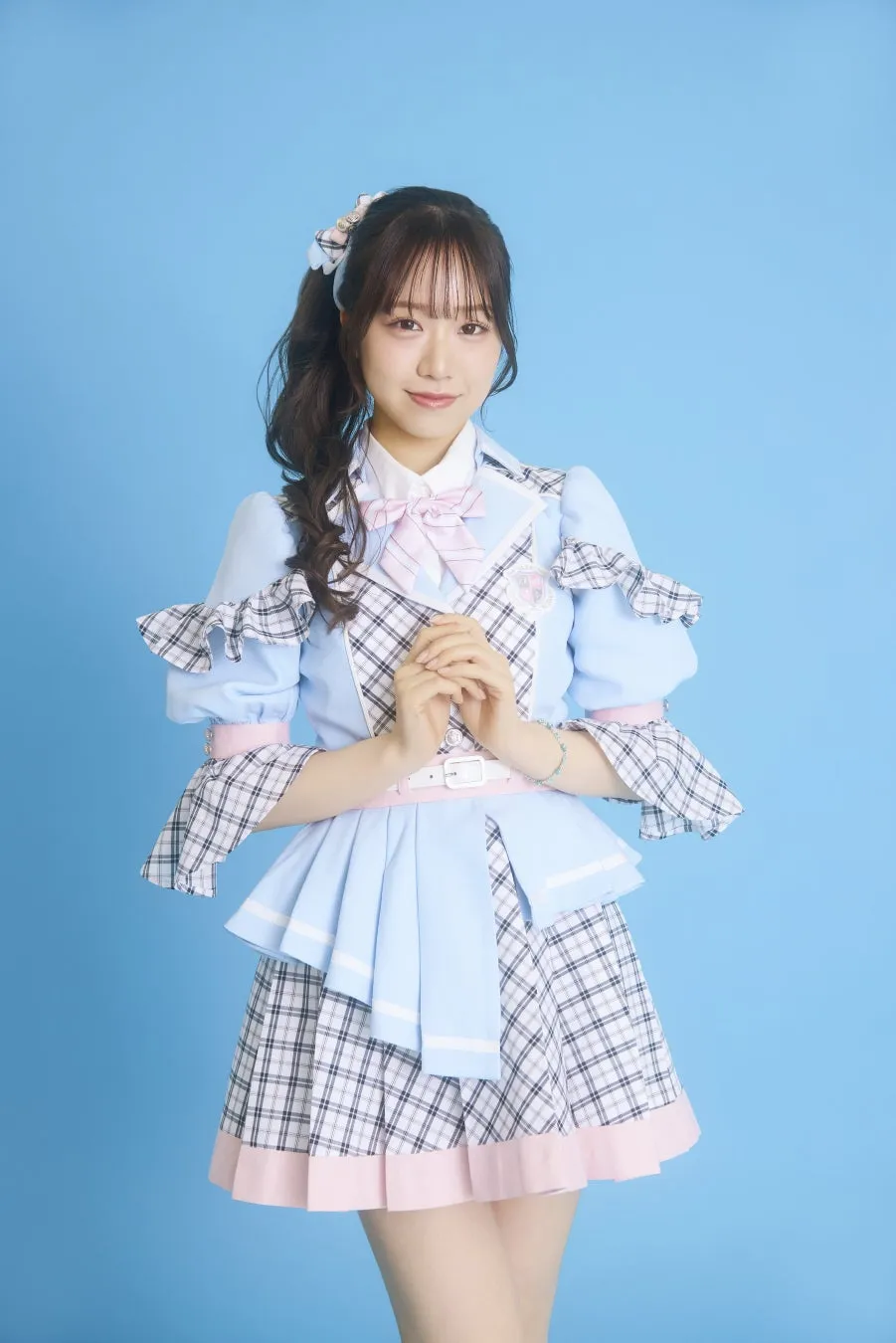 水色の衣装を着た女性のポートレート。彼女は髪をポニーテールにし、ピンクのリボンで飾っています。背景は水色です。