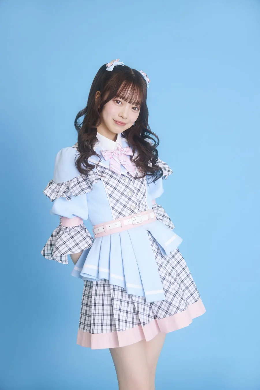 水色の衣装を着た女性のポートレート。彼女は笑顔で、背景は水色。