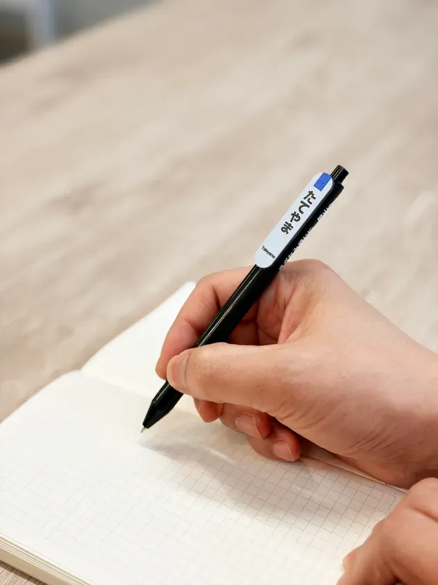 手帳にペンで文字を書いている様子