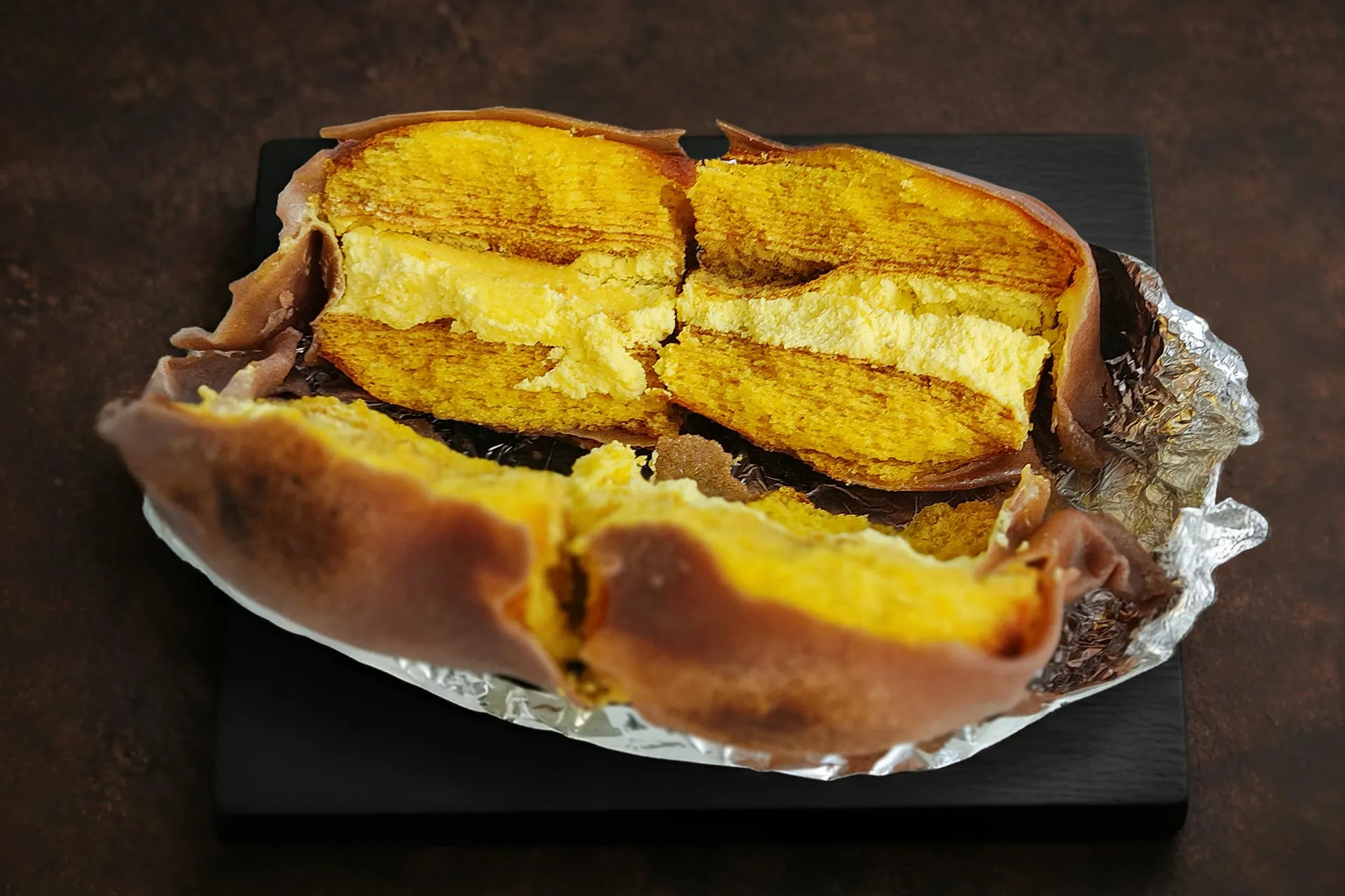 カットされた焼き芋のような食べ物。黄色い部分と茶色い部分があり、アルミホイルの上に載っている。