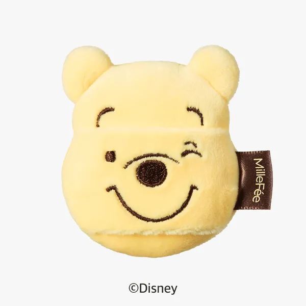 くまのプーさんの顔の形をした、黄色いぬいぐるみ。片目を閉じていて、茶色のタグが付いている。