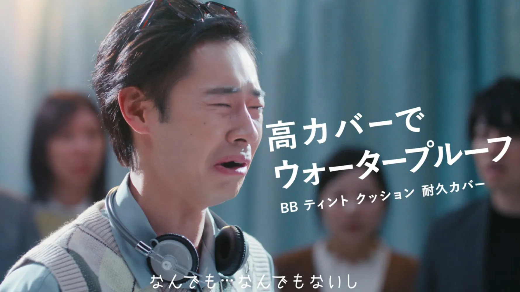 男性が涙を流している様子を捉えた画像。背景には他の人々がぼやけて映っています。画面には化粧品の広告テキストが重ねられています。