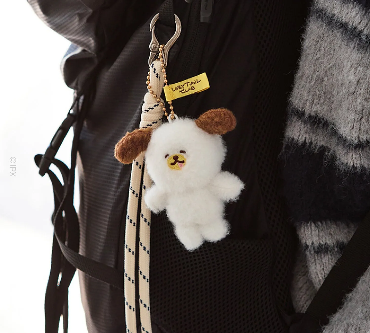 リュックサックに付けられた白い犬のぬいぐるみとタグ