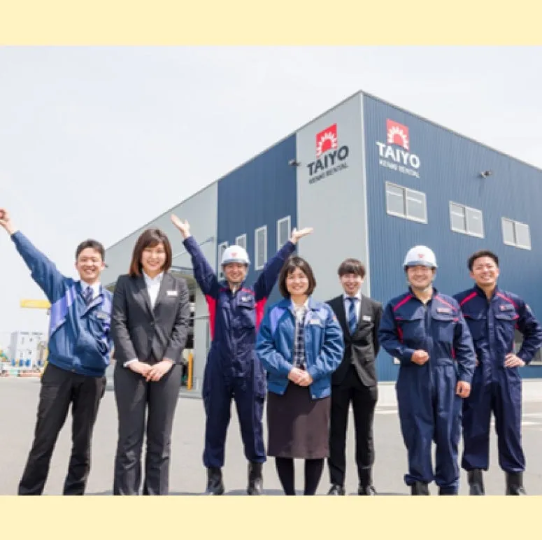 会社の前に立つ、様々な服装の男女のグループ写真