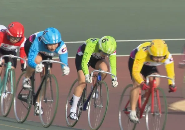 自転車競技のレースの様子。選手たちはヘルメットを被り、競技用の自転車に乗って競い合っている。