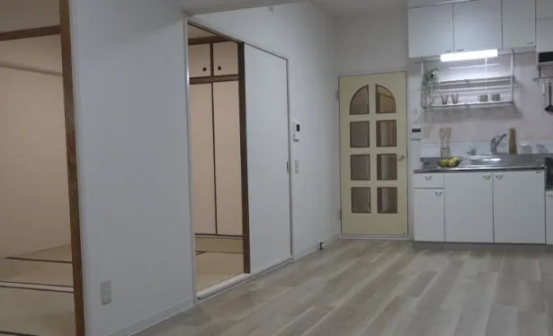 白い壁と木製のフレームで囲まれた和室と、白いキッチンとフローリングの洋室が隣接している部屋の写真です。