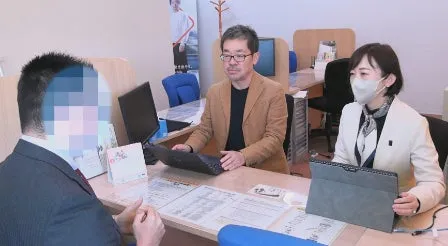 オフィスで、男性3人がテーブルを囲んで話をしている様子。男性の顔はぼかしが入っている。