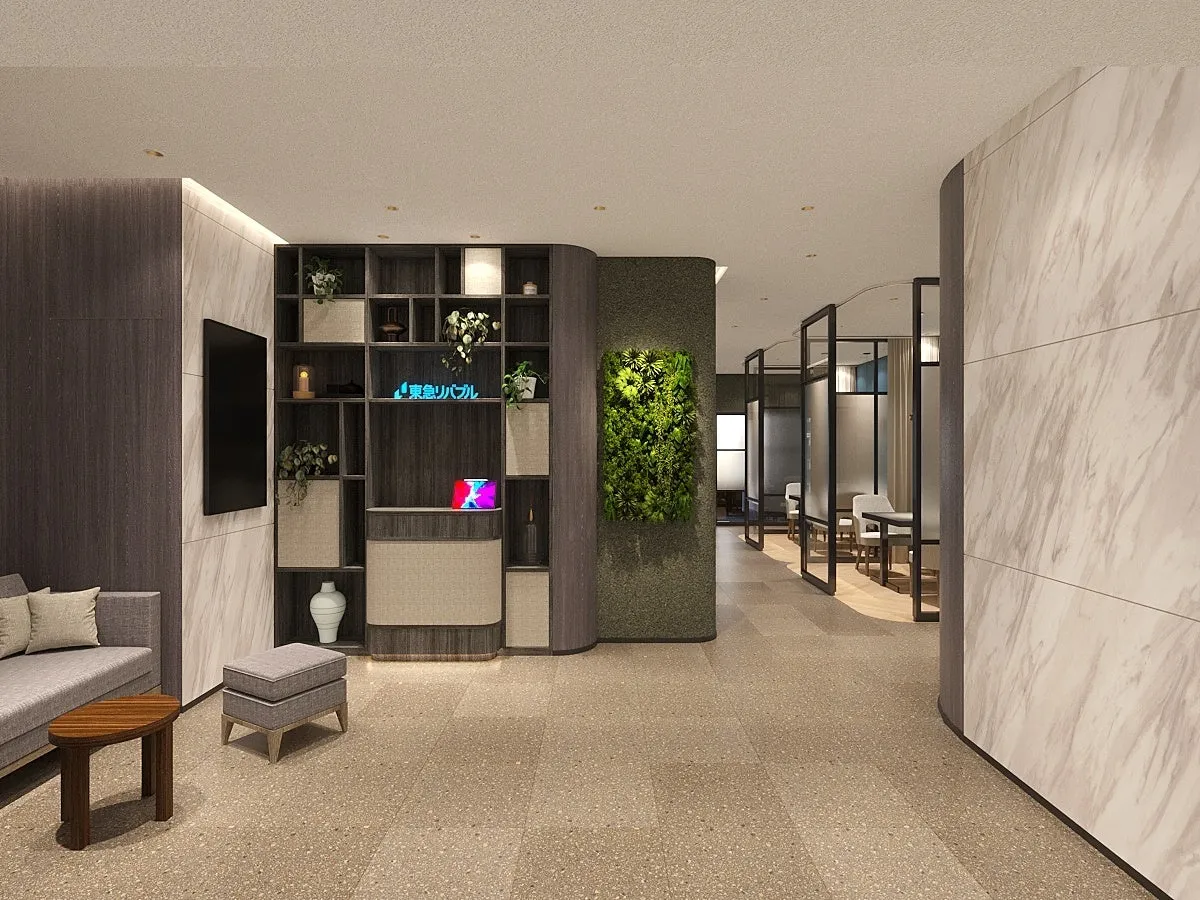 洗練された内装のオフィス空間を捉えた写真。木製の棚には植物や装飾品が飾られ、緑の壁がアクセントになっている。奥には個室が並び、モダンな雰囲気を醸し出している。