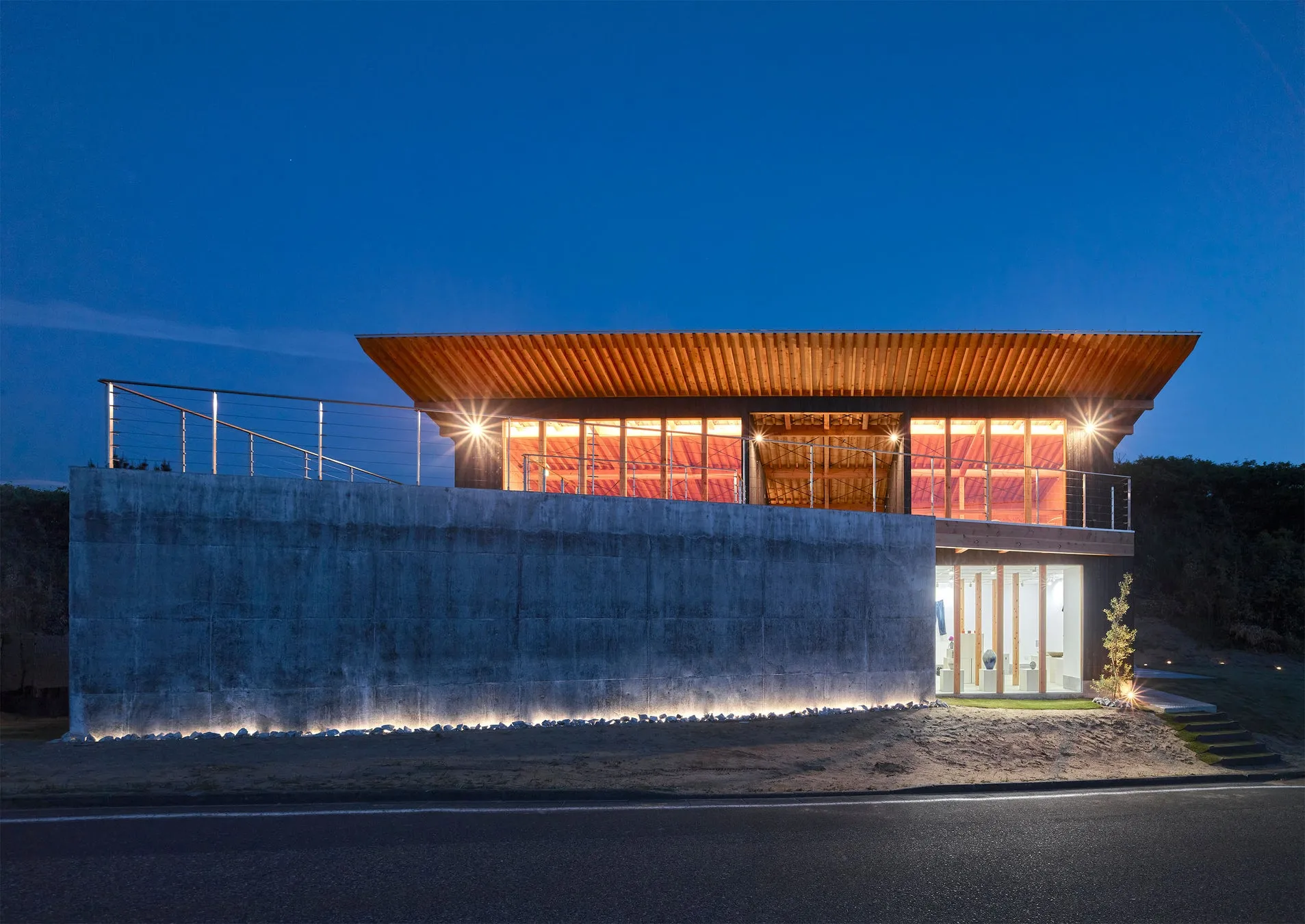 夜のモダンな建物。コンクリートの壁と木製の屋根が特徴
