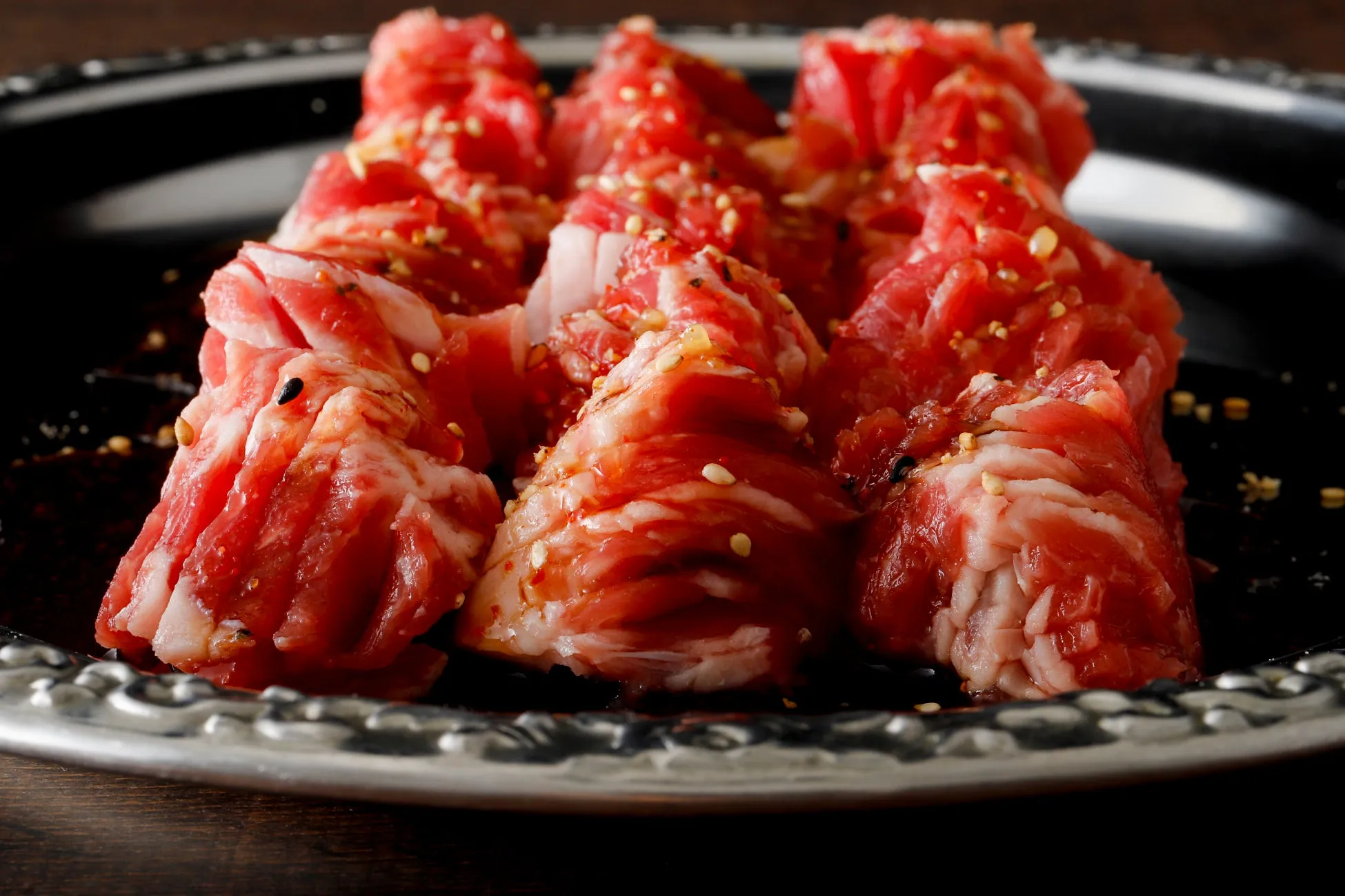 お皿に盛り付けられた、美味しそうな赤身肉のアップです。肉には白ごまがまぶされています。