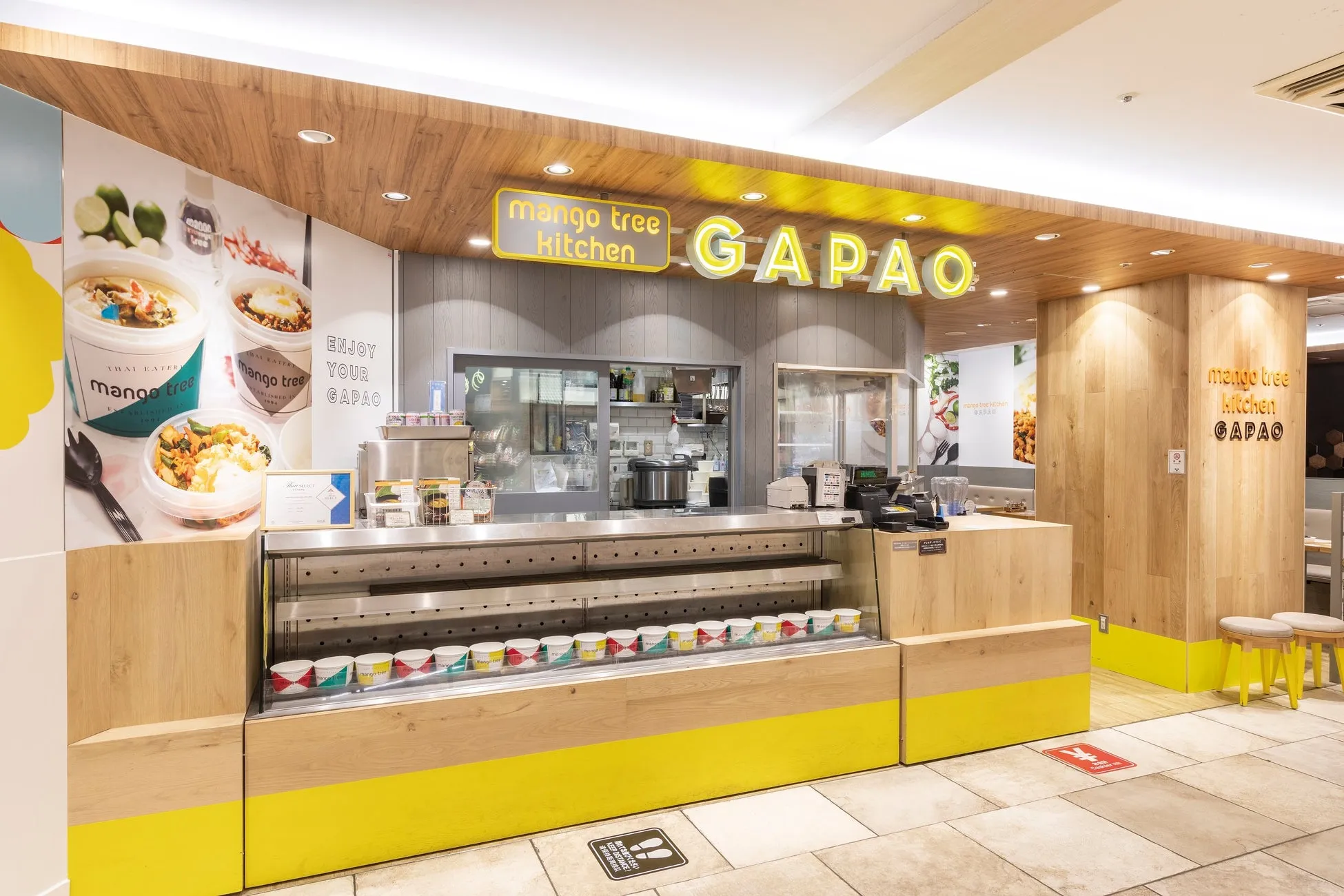 タイ料理レストラン「mango tree kitchen GAPAO」の店内の写真です。カウンターには料理が並び、店内は明るく清潔感があります。