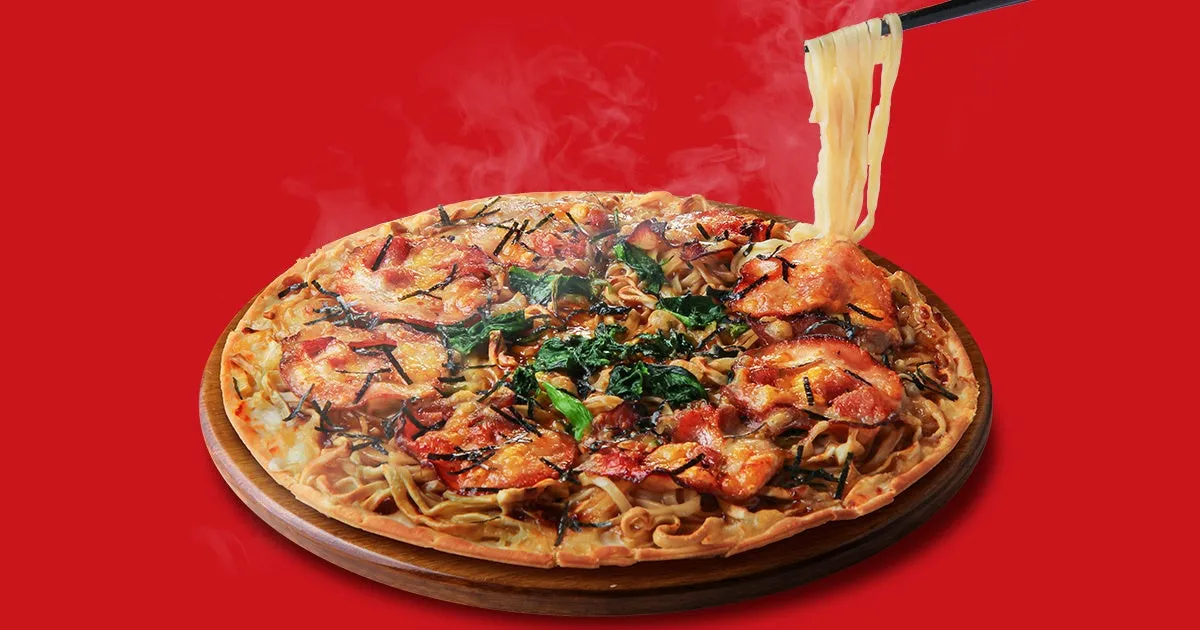 家系ラーメンピザのイメージ。麺がトッピングされ、ほうれん草、海苔、チャーシューのようなものが乗っている。