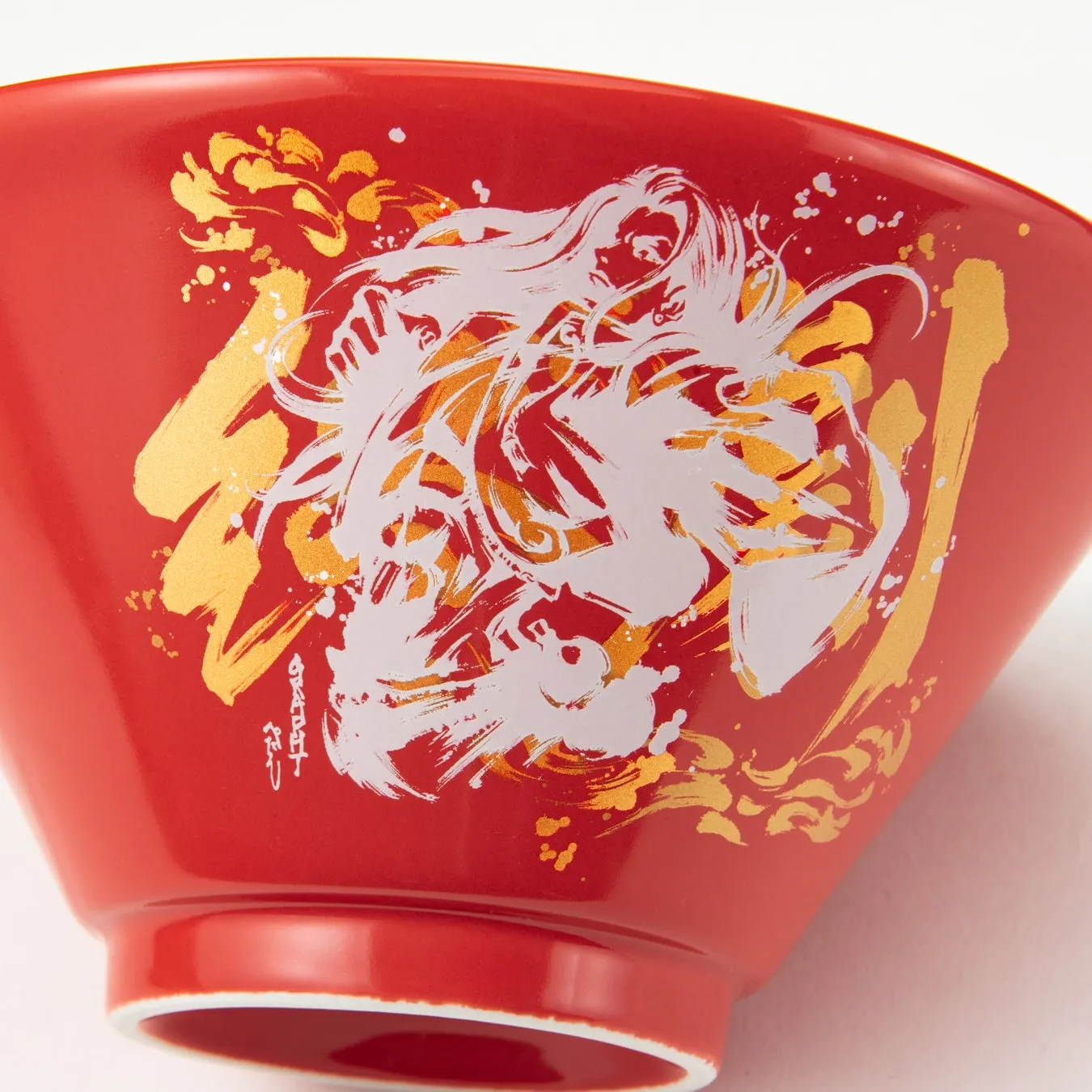 赤いラーメン鉢に女性のイラストが描かれている。金色の装飾が施されている。