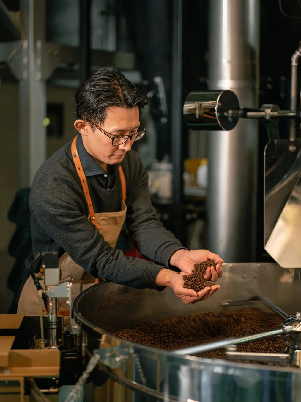 焙煎機の前でコーヒー豆の状態を確認する男性