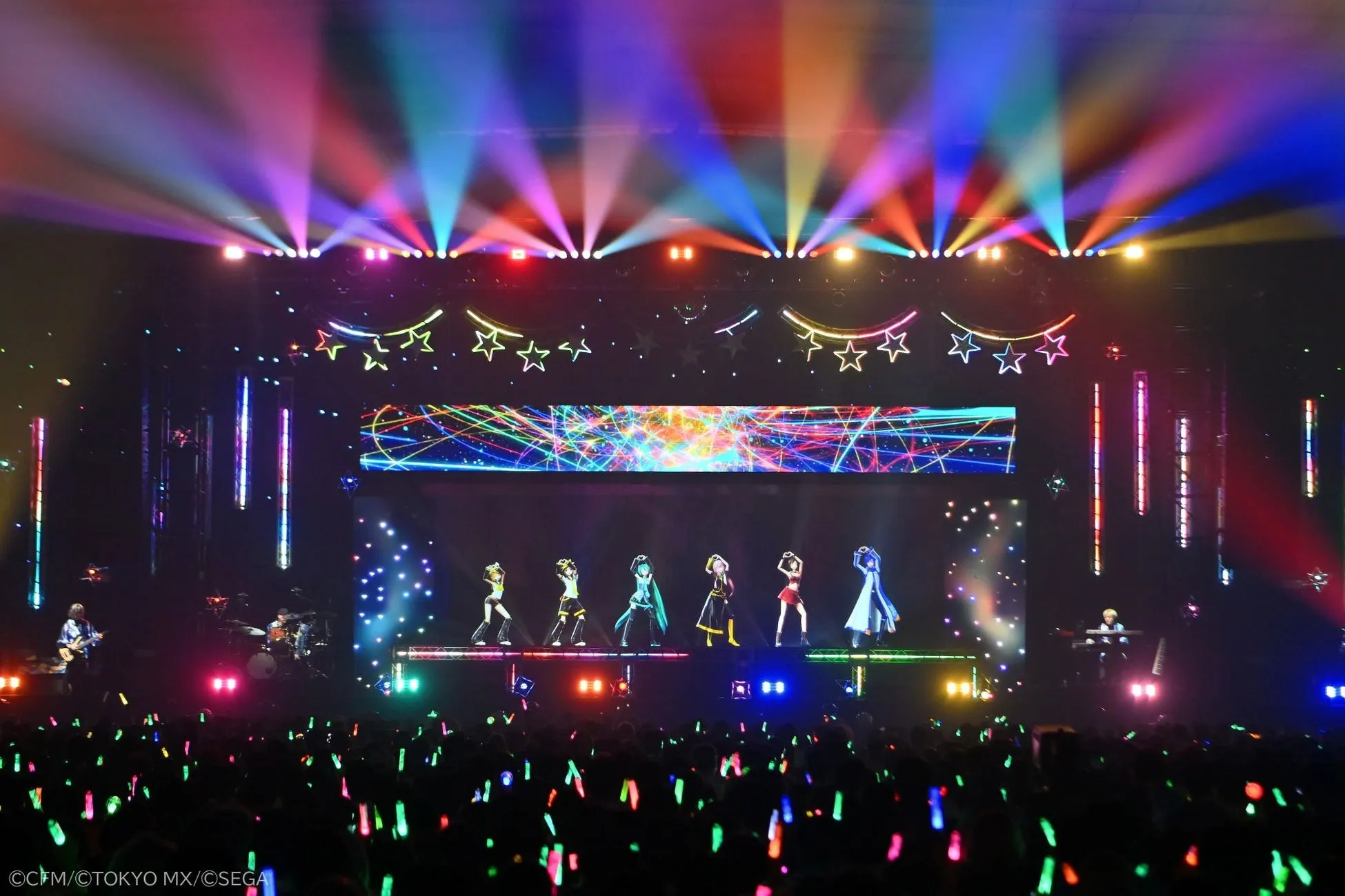 ステージでパフォーマンスをするアイドル達と、それを観客席から見守る観客の様子。