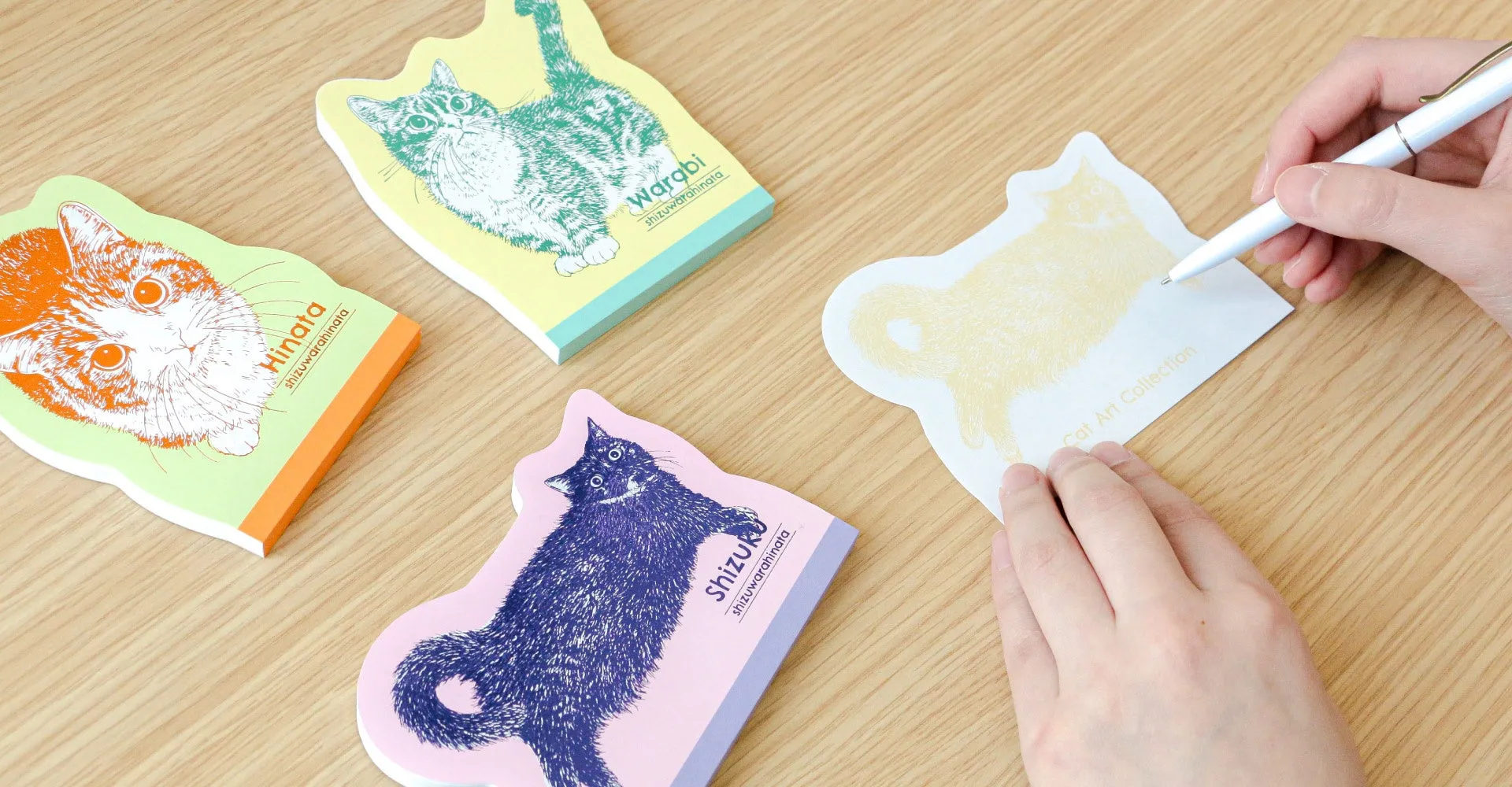 猫のイラストが描かれた付箋紙に文字を書く様子