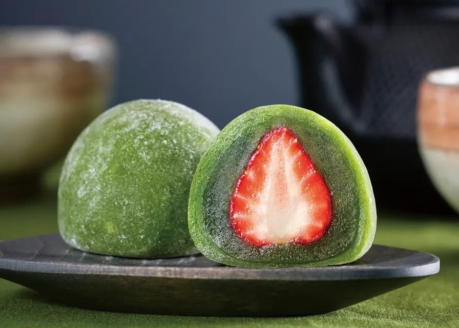 いちご大福が2つ、黒いお皿に載せられている様子。1つは半分にカットされており、断面が見えている。