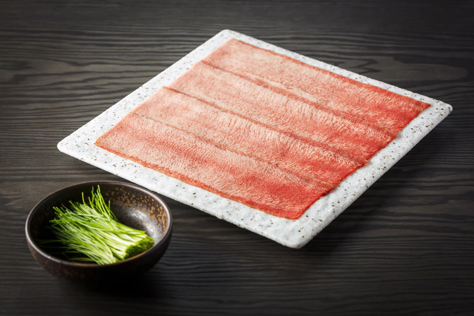 お皿に盛られた生の牛肉と、薬味のネギ