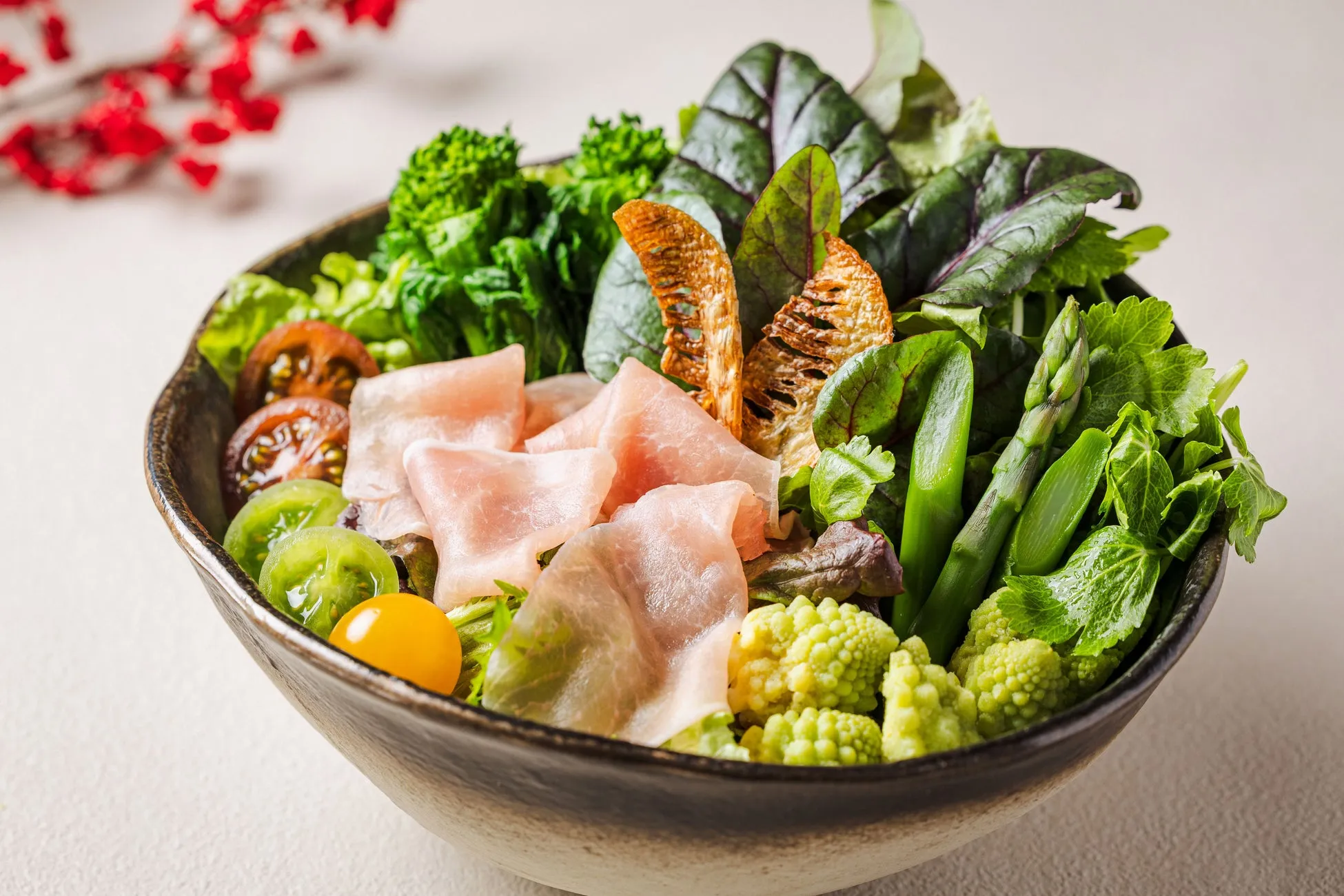 色とりどりの野菜と生ハムが盛り付けられたサラダボウル。