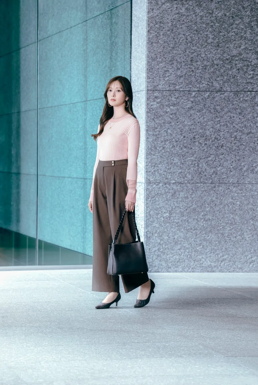 ピンクのトップスと茶色のパンツを着た女性の着用イメージ