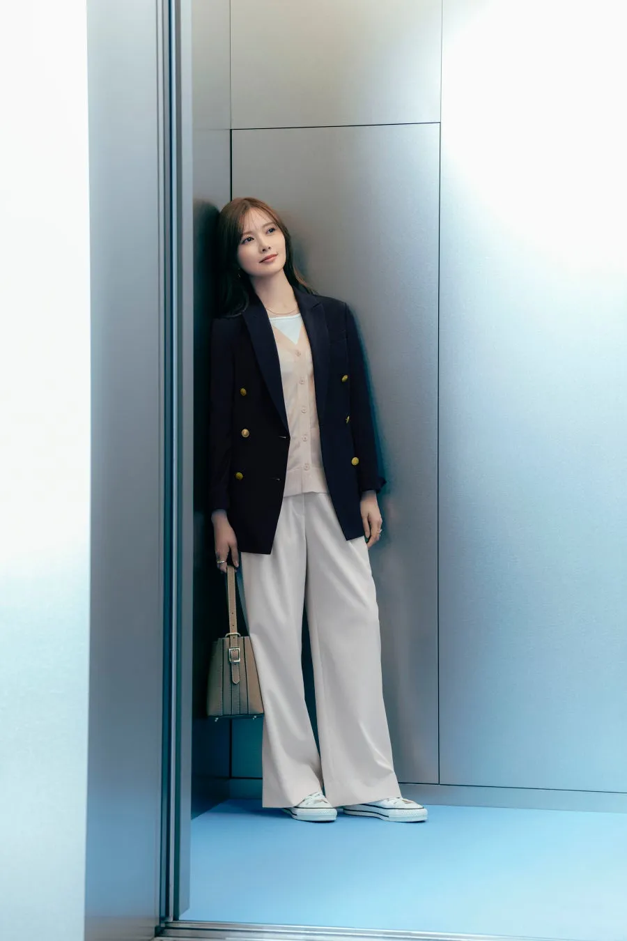 エレベーターの隅に寄りかかって遠くを見つめる女性の着用イメージ